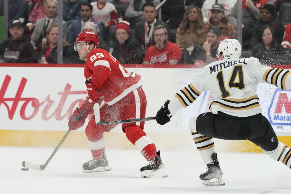 Detroit Red Wings right wing Alex DeBrincat (93) looks to pass as Boston Bruins defenseman Ian Mitchell (14) dedends during the second period of an NHL hockey game, Saturday, Nov. 4, 2023, in Detroit. (AP Photo/Carlos Osorio)