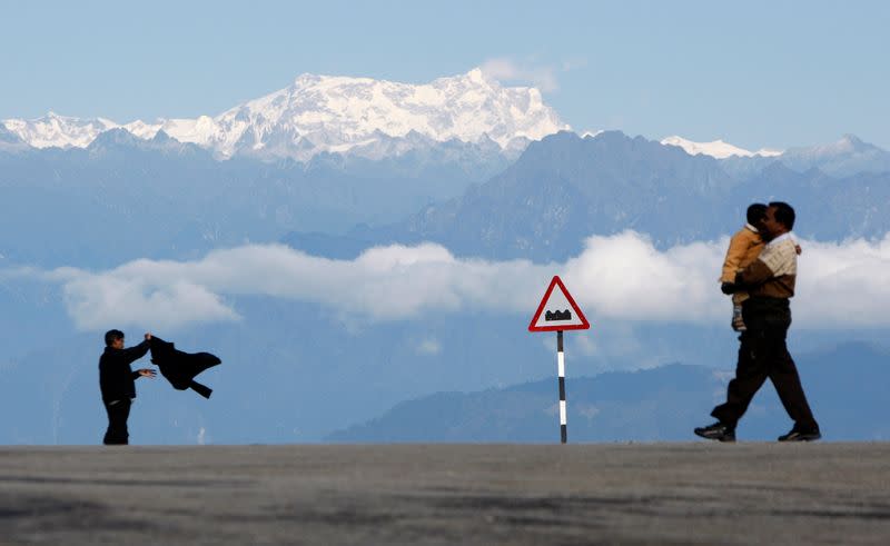 FILE PHOTO: A man with a child walks in front of the Gankar Punsun glacier at Dochula