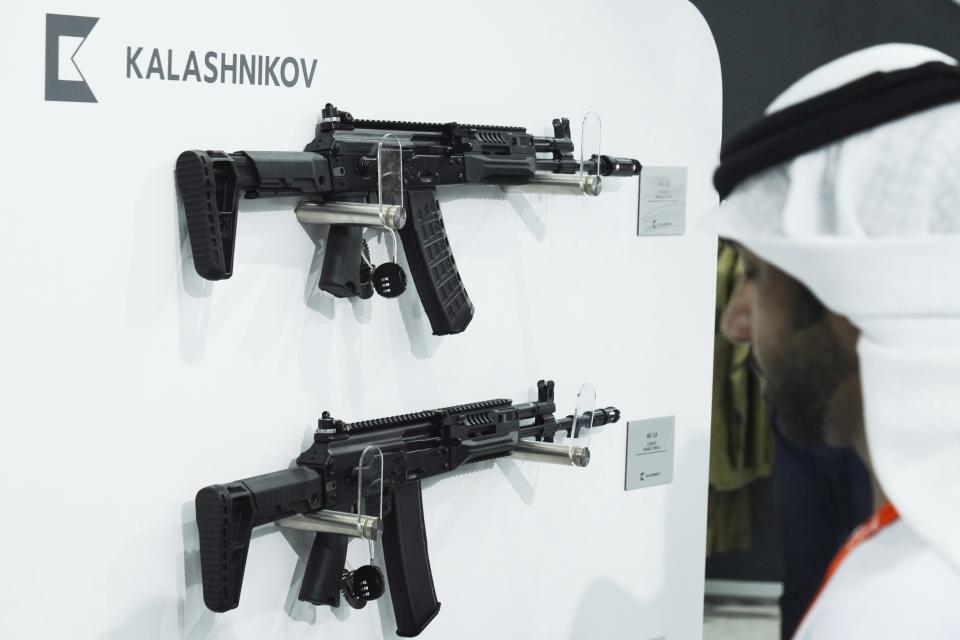 An Emirati man walks past Kalashnikov rifles at a tent for Russian weapons manufacturers at the International Defense Exhibition and Conference in Abu Dhabi, United Arab Emirates, Monday, Feb. 20, 2023. Just outside of Abu Dhabi's biennial arms fair in a large tent, Russia offered weapons for sale Monday ranging from Kalashnikov assault rifles to missile systems despite facing sanctions from the West over its war on Ukraine. (AP Photo/Jon Gambrell)