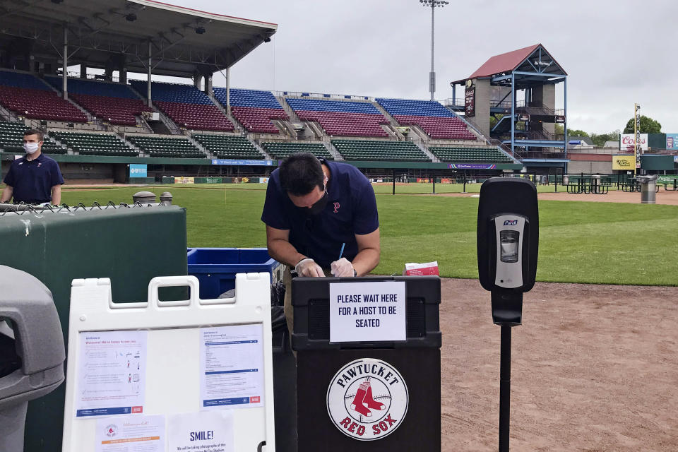 A worker prepares for guests to dine on the field at McCoy Stadium, home of the Pawtucket Red Sox, in Pawtucket, Rhode Island, Wednesday, May 27, 2020. With the minor league baseball season on hold due to the coronavirus pandemic, the Triple-A affiliate of the Boston Red Sox had found another use for its home field. Starting next weekend, “Dining on the Diamond” will allow PawSox fans and others just longing for a taste of baseball to sample typical ballpark fare on the McCoy Stadium infield.(AP Photo/Jimmy Golen)