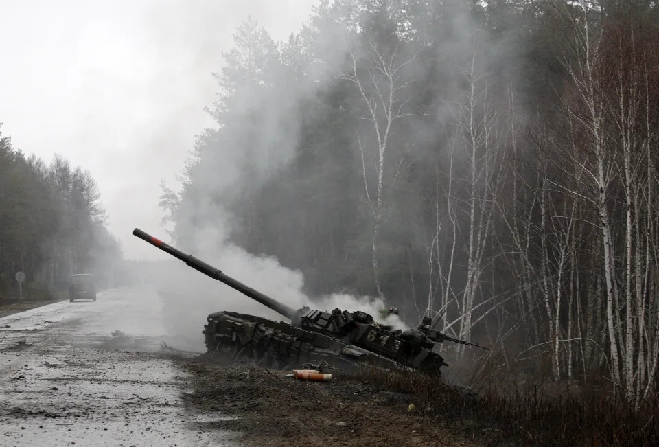 TOPSHOT - Smoke rises from a Russian tank destroyed by the Ukrainian forces on the side of a road in Lugansk region on February 26, 2022. - Russia on February 26 ordered its troops to advance in Ukraine 