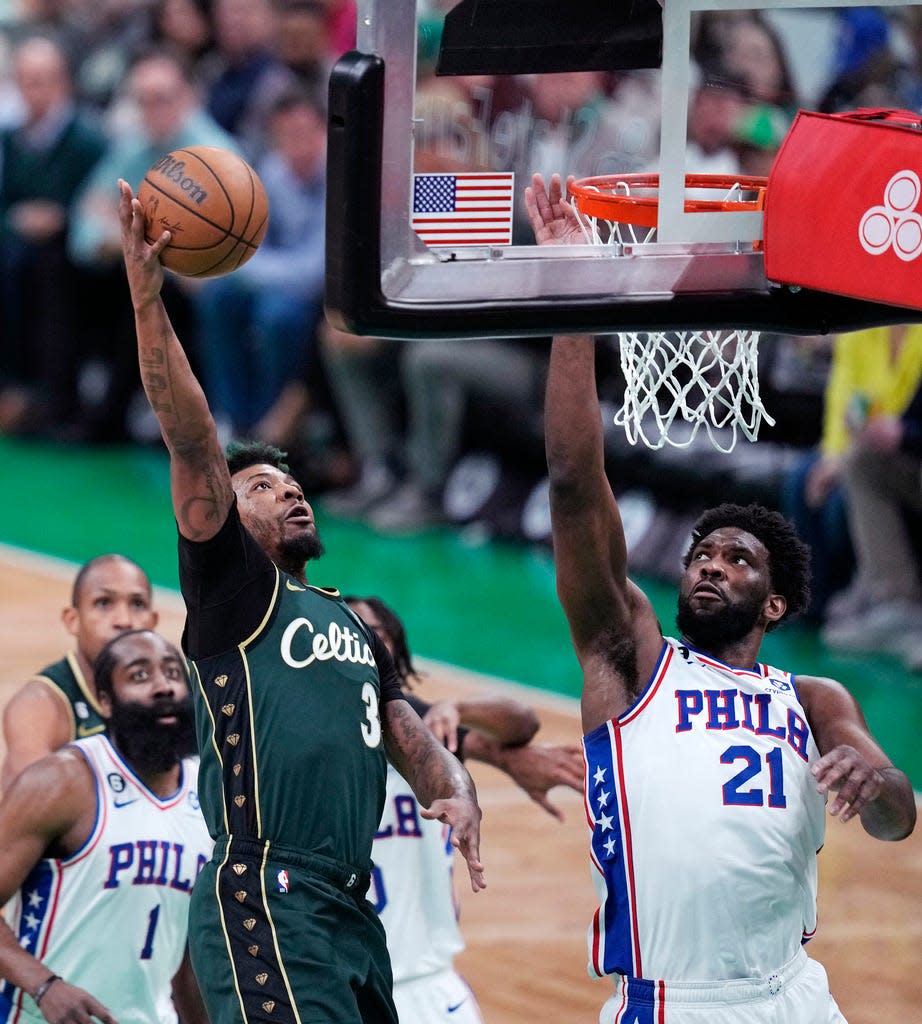 Boston Celtics guard Marcus Smart, left, drives to the basket against Philadelphia 76ers center Joel Embiid (21) during the first half of Game 5 of the NBA basketball Eastern Conference semifinals Tuesday, May 9, 2023, in Boston. (AP Photo/Charles Krupa)