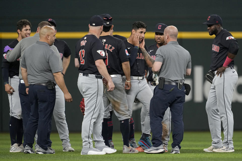 Cleveland Guardians' Tyler Freeman, left, and shortstop Brayan Rocchi, center right, holding his jaw, are checked on by manager Stephen Vogt (12) and staff after the two collided making a play on a fly out by Texas Rangers' Adolis Garcia in the fifth inning of a baseball game, Tuesday, May 14, 2024, in Arlington, Texas. Freemand made the catch on the play. (AP Photo/Tony Gutierrez)