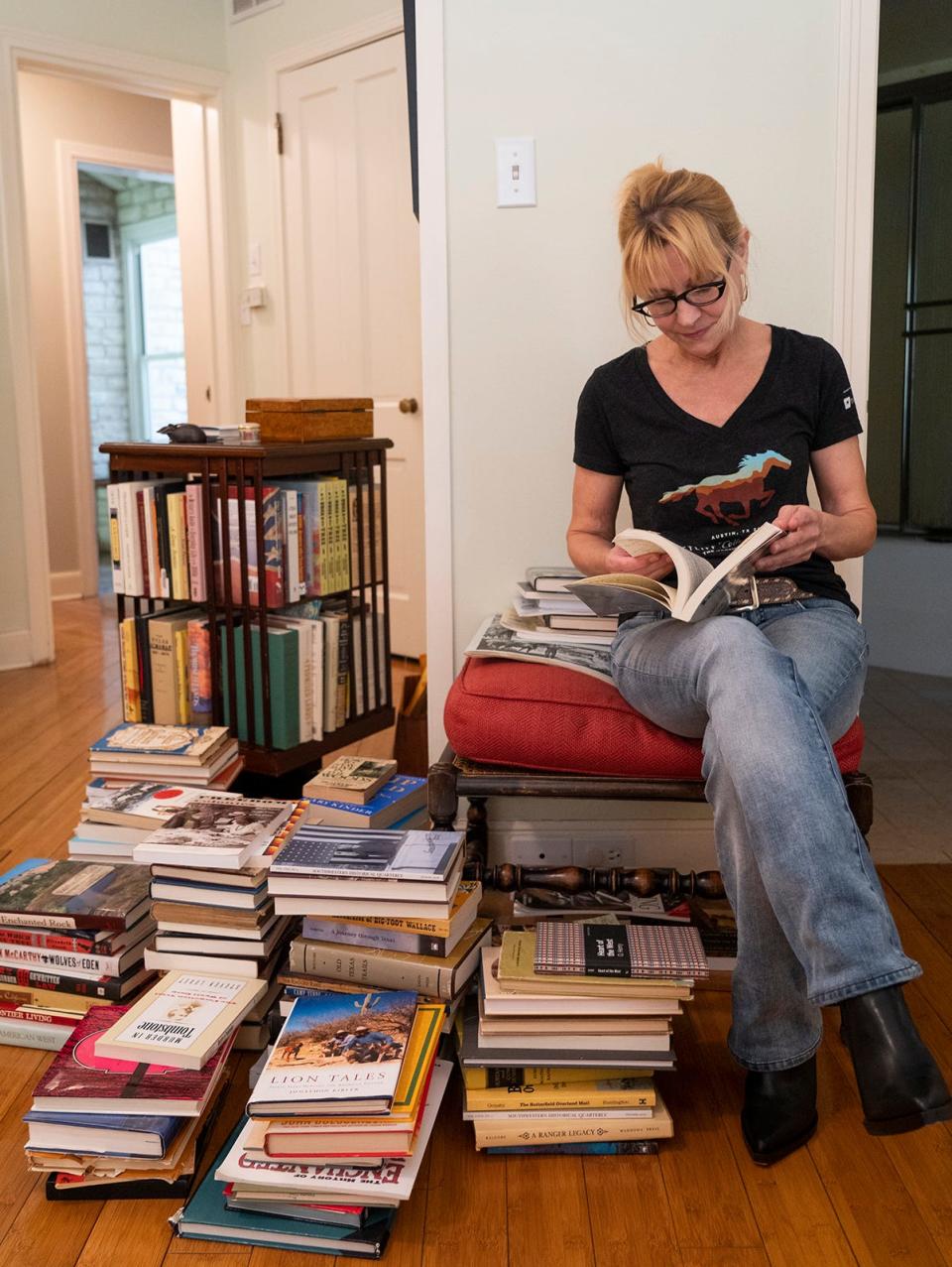 Elizabeth Crook at home, looking through some of the books she uses for historical research. Background material for each novel is organized into separate stack groups.