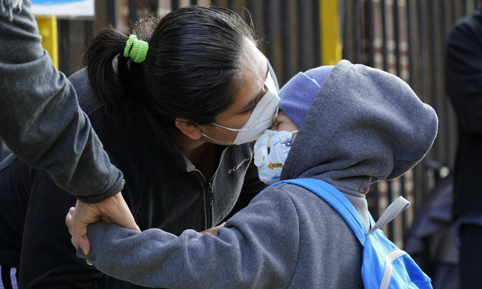 Maria Flores kisses her son Pedro Garcia, 4, while a teacher takes his hand as he arrives for the first day of school at the Mosaic Pre-K Center in Queens, Monday, Sept. 21, 2020, in New York. The city public schools delayed reopening for two weeks. (AP Photo/Mark Lennihan)