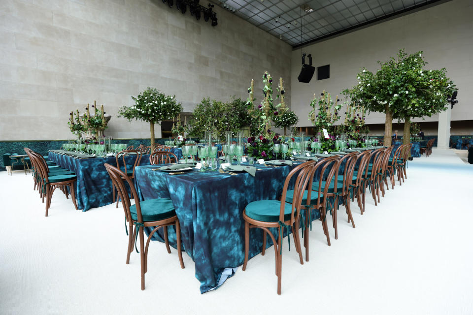 Elegant event setup with long tables, tall floral centerpieces, and chairs inside the Met Gala