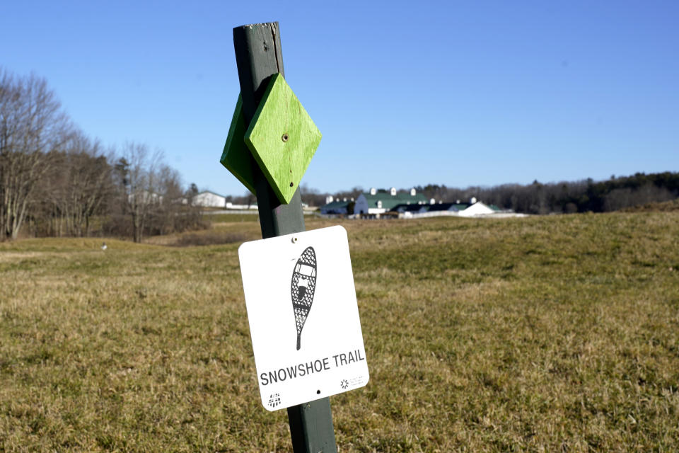 A trail sign for a snowshoeing route is seen on a snowless field at Pineland Farms, Thursday, Dec. 21, 2023, in New Gloucester, Maine. Unseasonably warm weather, including rain storms in the northeast, is washing away snow at ski areas and reducing the chances that many people in the U.S. will experience a white Christmas this year. (AP Photo/Robert F. Bukaty)