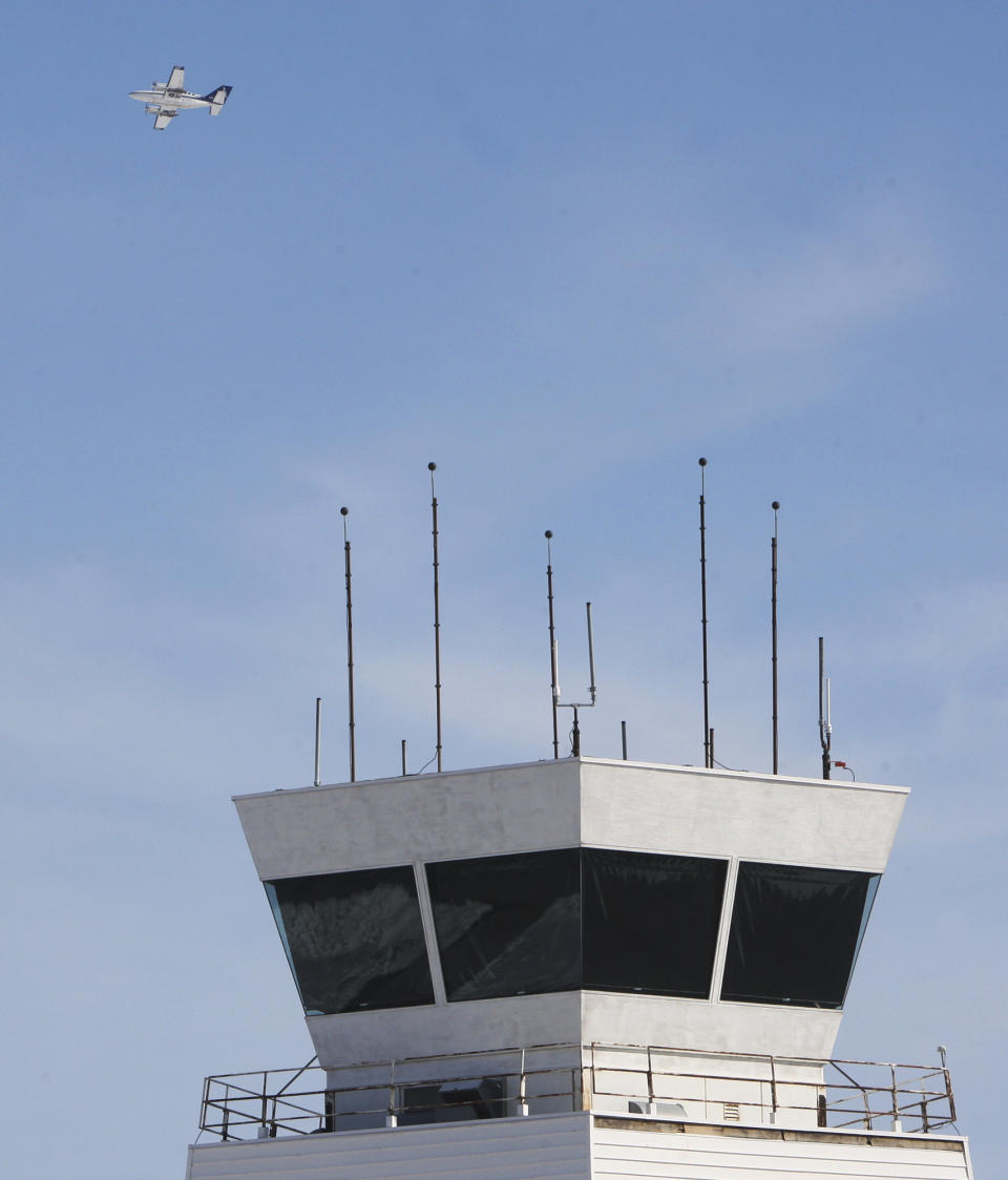 FILE - In this Feb. 25, 2013 file photo, a twin-engine airplane flies past the air traffic control tower at St. Louis Regional Airport in Bethalto, Ill. Under orders to trim hundreds of millions of dollars from its budget, the Federal Aviation Administration released a final list Friday, March 22, 2013, of 149 air traffic control facilities that it will close at small airports around the country starting early next month. The tower at St. Louis Regional was included on that list. (AP Photo/The Telegraph, John Badman, File)