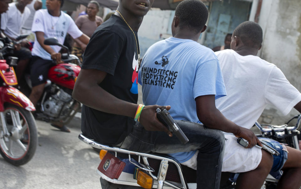 In this May 22, 2019 photo, gang members patrol the street holding guns six months after a massacre in the La Saline slum of Port-au-Prince, Haiti. “Gangs are multiplying because the government is weak,” said Paul Eronce Villard, Haiti’s general prosecutor, who estimates there are more than 50 gangs now operating. “It’s a real challenge for police.” (AP Photo/Dieu Nalio Chery)