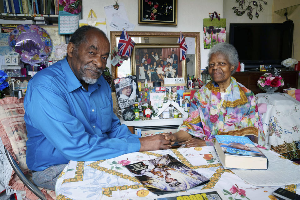 Sylius and Bridgette Toussaint pose for a photo at their home in Preston, England, Tuesday, April 25, 2023. The pair as children in Dominica remember the coronation of Elizabeth II which took place at Westminster Abbey on 2 June 1953. Sylius Toussaint, now 83, still remembers the coronation song he learned seven decades ago, chuckling as he softly croons out the blessing for "our queen who is crowned today," only occasionally stumbling over a phrase lost to the passage of time. (AP Photo/Jon Super)