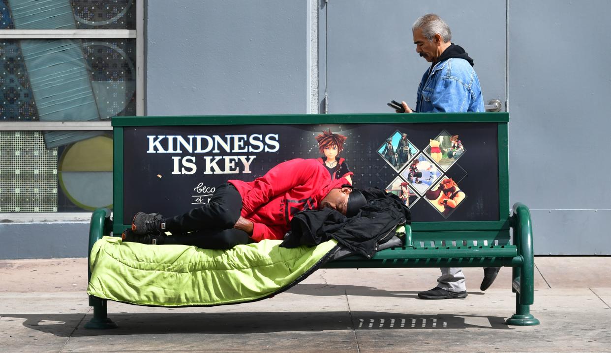 A man sleeps on bench near a bus stop in Los Angeles, California on March 17, 2020. - Cities across the nation are worried about the homeless population as the coronavirus pandemic surges with the US death toll reaching 100. (Photo by Frederic J. BROWN / AFP) (Photo by FREDERIC J. BROWN/AFP via Getty Images)