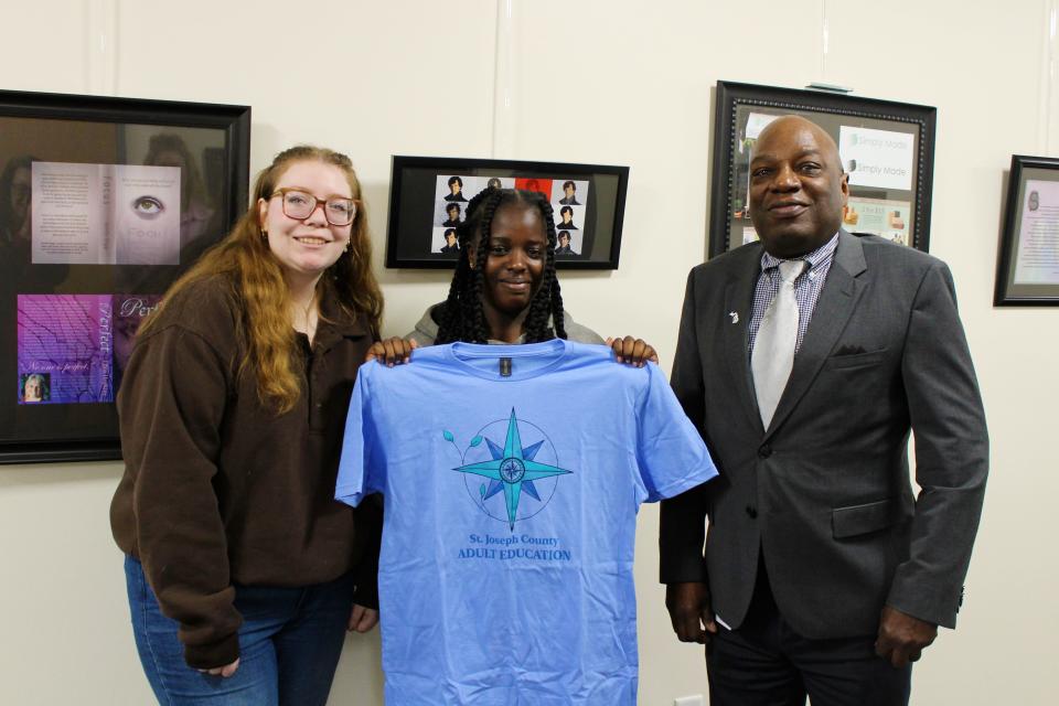 Ciera Kline, Jalisa Pope and Lanre Ajayi, dean of advanced technologies and public services, pose for a photo with Pope's winning logo design.