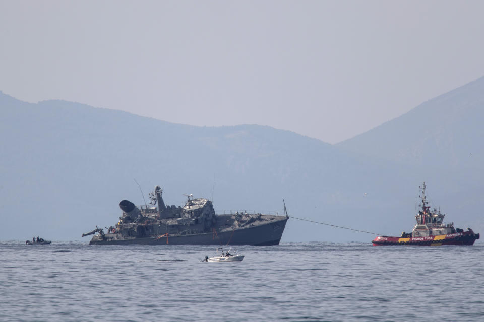 Α damaged navy minesweeper is being towed near the port of Piraeus, Greece, on Tuesday, Oct. 27, 2020. Greece's coast guard says a Greek navy minesweeper and a Portuguese-flagged cargo ship have collided outside the country's main port of Piraeus, leaving two navy crew slightly injured and prompting the evacuation of the military vessel. (AP Photo/Petros Giannakouris)