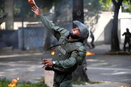 A riot security force throws a piece of brick at a rally during a strike called to protest against Venezuelan President Nicolas Maduro's government in Caracas. REUTERS/Andres Martinez Casares