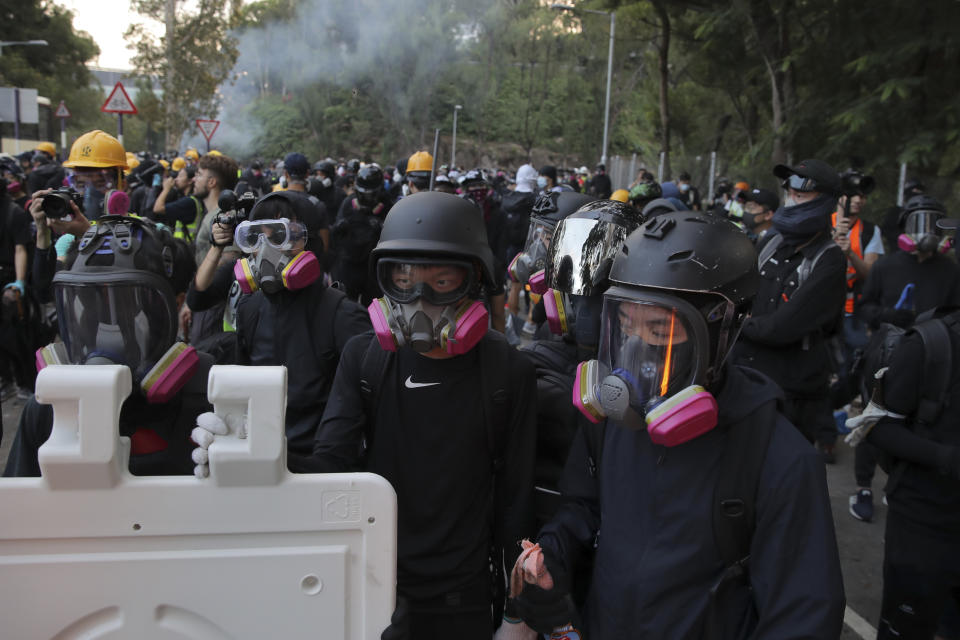 Students with gas masks stand watch behind barricades after a faced-off with riot police at the Chinese University in Hong Kong, Tuesday, Nov. 12, 2019. Police fired tear gas at protesters who littered streets with bricks and disrupted morning commutes and lunch breaks Tuesday after an especially violent day in Hong Kong's five months of anti-government demonstrations. (AP Photo/Kin Cheung)