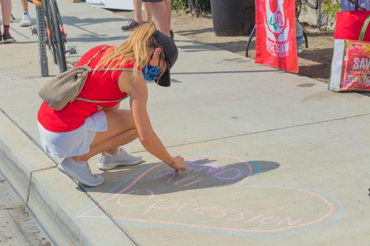 Woman writing with Chalk on sidewalk