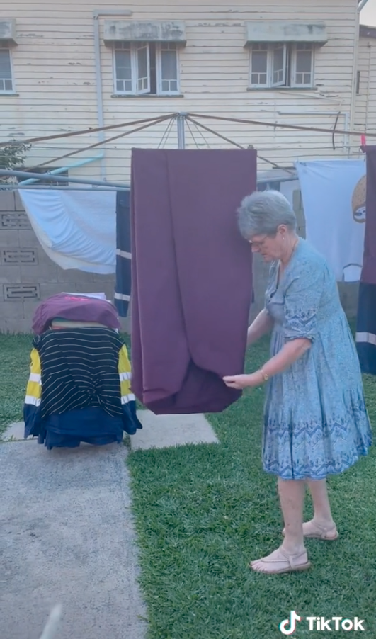 Woman folding a fitted sheet on a clothes line