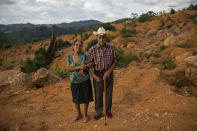 Alejandro Mejia, 80, and his wife, Petrona Caballero, 80, stand for a portrait at the site of their home destroyed by a landslide triggered by hurricanes Eta and Iota in the village of La Reina, Honduras, Saturday, June 26, 2021. They had been living together here for 48 years. Mejia built his own house. "I made a wooden box. I threw mud with pine needles on it and let it sun and dry for six days, protecting it from the rain." Caballero says, "In one's own home, one rests one's thoughts. ... I feel a wound, an affliction in my chest. We will suffer from now on." (AP Photo/Rodrigo Abd)