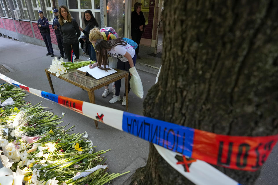 A girl signs the book of condolences in the Vladimir Ribnikar school, two days after a 13-year-old boy used his father's guns to kill eight fellow students and a guard, in Belgrade, Serbia, Friday, May 5, 2023. The bloodshed sent shockwaves through a Balkan nation scarred by wars, but unused to mass murders. (AP Photo/Darko Vojinovic)