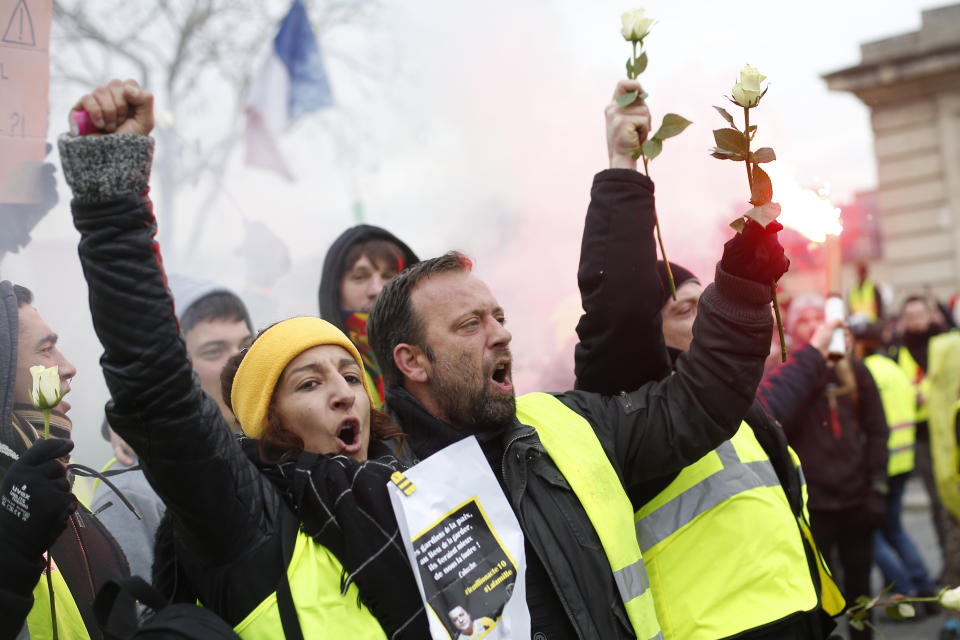 Yellow vest protesters hold white roses during a march Saturday, Jan. 19, 2019 in Paris. Yellow vest protesters are planning rallies in several French cities despite a national debate launched this week by President Emmanuel Macron aimed at assuaging their anger. (AP Photo/Thibault Camus)