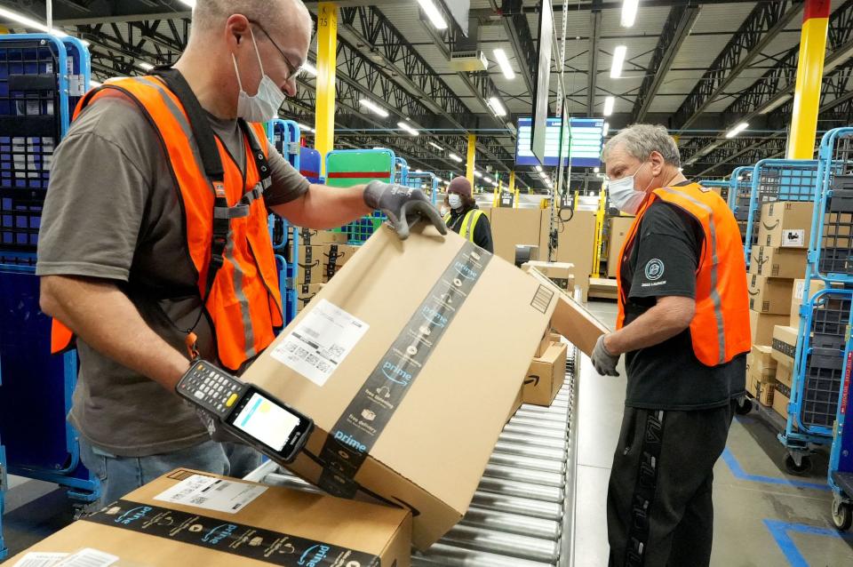 Jonathan Handy, left, and Mark McCredie check in packages going to other locations at the Amazon Fulfillment Center in Oxnard on Thursday.