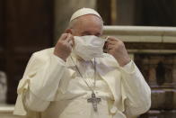 FILE - In this Tuesday, Oct. 20, 2020 file photo, Pope Francis puts on his face mask as he attends an inter-religious ceremony for peace in the Basilica of Santa Maria in Aracoeli, in Rome. Pope Francis’ decision to forego wearing a face mask has been noticed, with some concern, by the commission of Vatican experts he appointed to help chart the Catholic Church’s path through the coronavirus pandemic and the aftermath. The Rev. Augusto Zampini, one of the key members of the pope’s COVID-19 commission, acknowledged Tuesday that at age 83 and with part of his lung removed, Francis would be at high risk for complications if he were to become infected with COVID-19.(AP Photo/Gregorio Borgia, File)