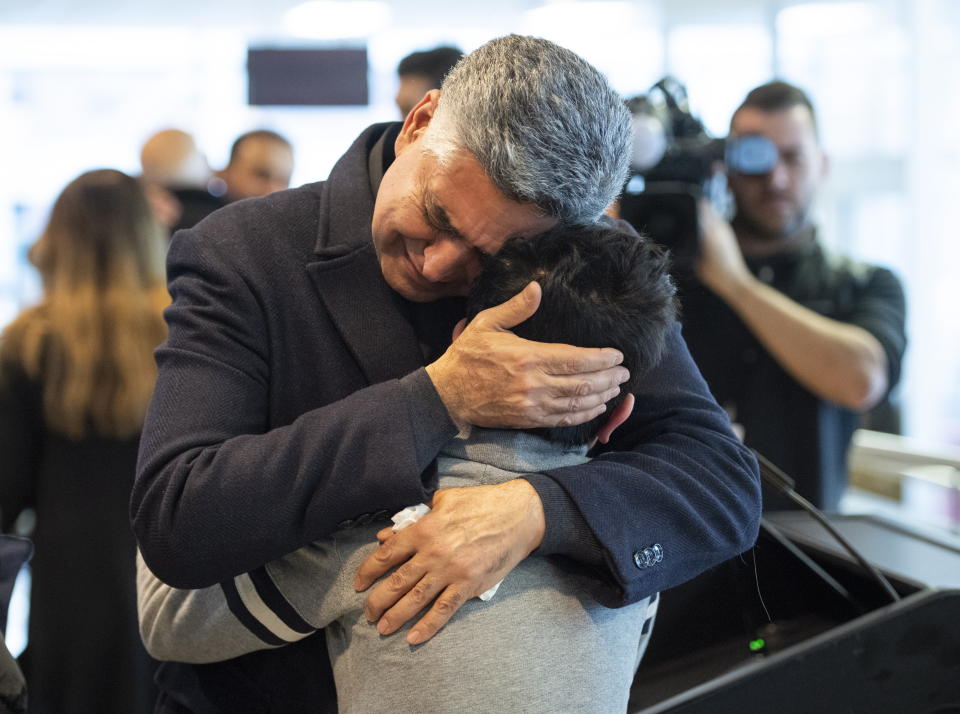 Ryan Pourjam, 13, son of Mansour Pourjam, is embraced by family friend Mahmoud Rastgou, after a ceremony Wednesday, Jan. 15, 2020 at Carleton University to honour Pourjam, a biology alumnus, and biology PhD student Fareed Arasteh, who died in the crash of Ukraine International Airlines Flight PS752 in Tehran. (Justin Tang/The Canadian Press via AP)