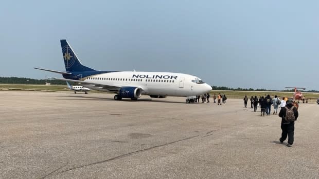 Evacuees from Deer Lake First Nation board a plane as nearby forest fires threaten to reach the community. (Submitted by resident of Deer Lake - image credit)