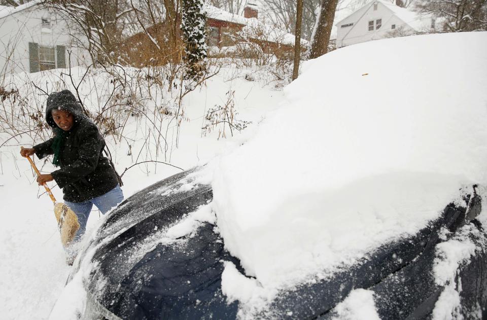 Oretha Bailey clears her car of snow in Silver Spring
