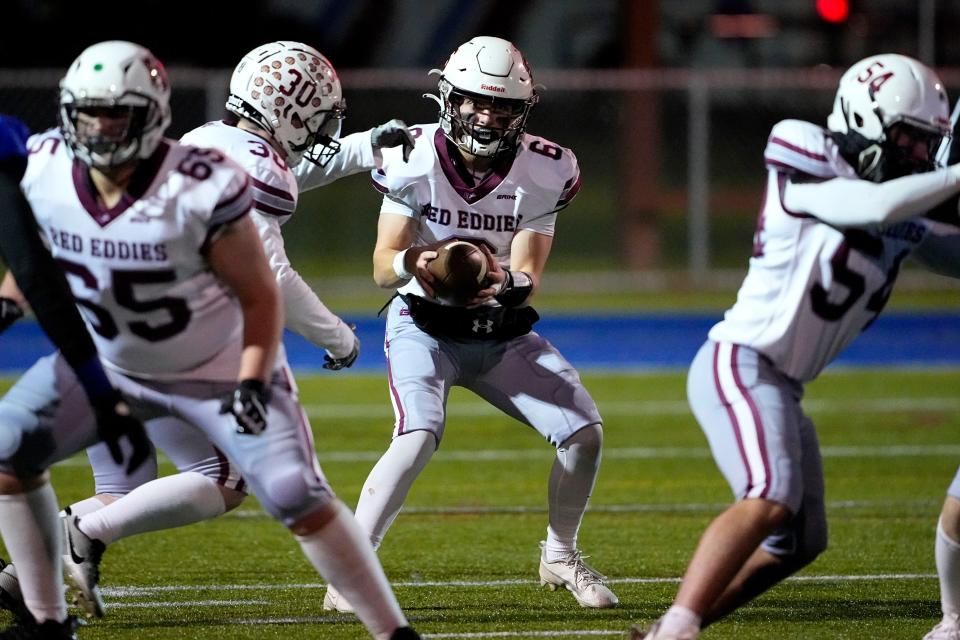 Edward Little High School quarterback Kade Masselli (6) takes the snap, Wednesday, Nov. 1, 2023, during a high school football game against Lewiston High School in Lewiston, Maine. Locals seek a return to normalcy after a mass shooting on Oct. 25. (AP Photo/Matt York)