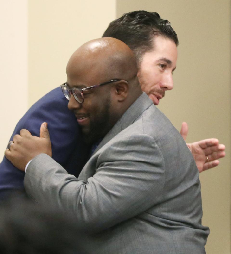 N.J. Akbar, president of the Akron school board, hugs Derrick Hall, board vice president, after being presented with a ceremonial gravel at Monday's board meeting. Hall was later elected the new board president at the meeting.