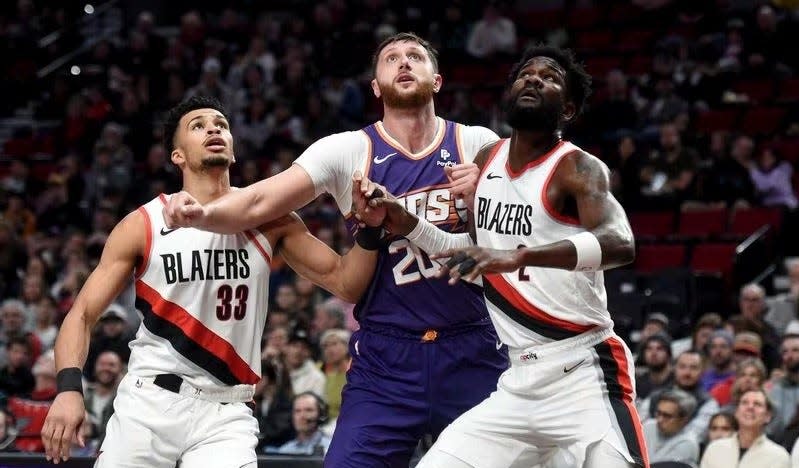 Phoenix Suns center Jusuf Nurkic, center, battles for position with Portland Trail Blazers forward Toumani Camara, left, and center Deandre Ayton, right, during the first half of an NBA basketball game in Portland, Ore., Tuesday, Dec. 19, 2023. All three were included in the Damian Lillard blockbuster trade in the offseason.