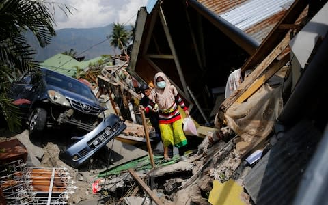 A woman makes her way through the rubble of houses in Balaroa neighborhood in Palu - Credit: AP