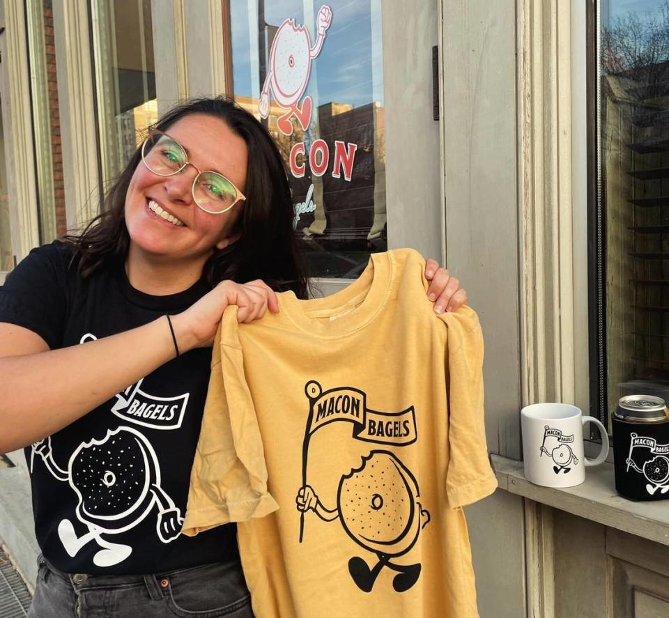 Macon Bagels owner Lauren Bone holds up Macon Bagel merchandise outside of her downtown bagel shop.