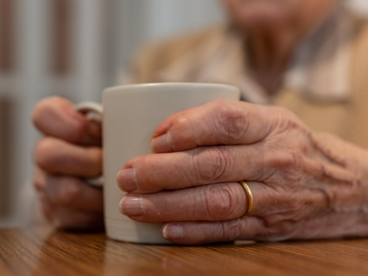 Senior woman warms up holding a hot drink in a mug