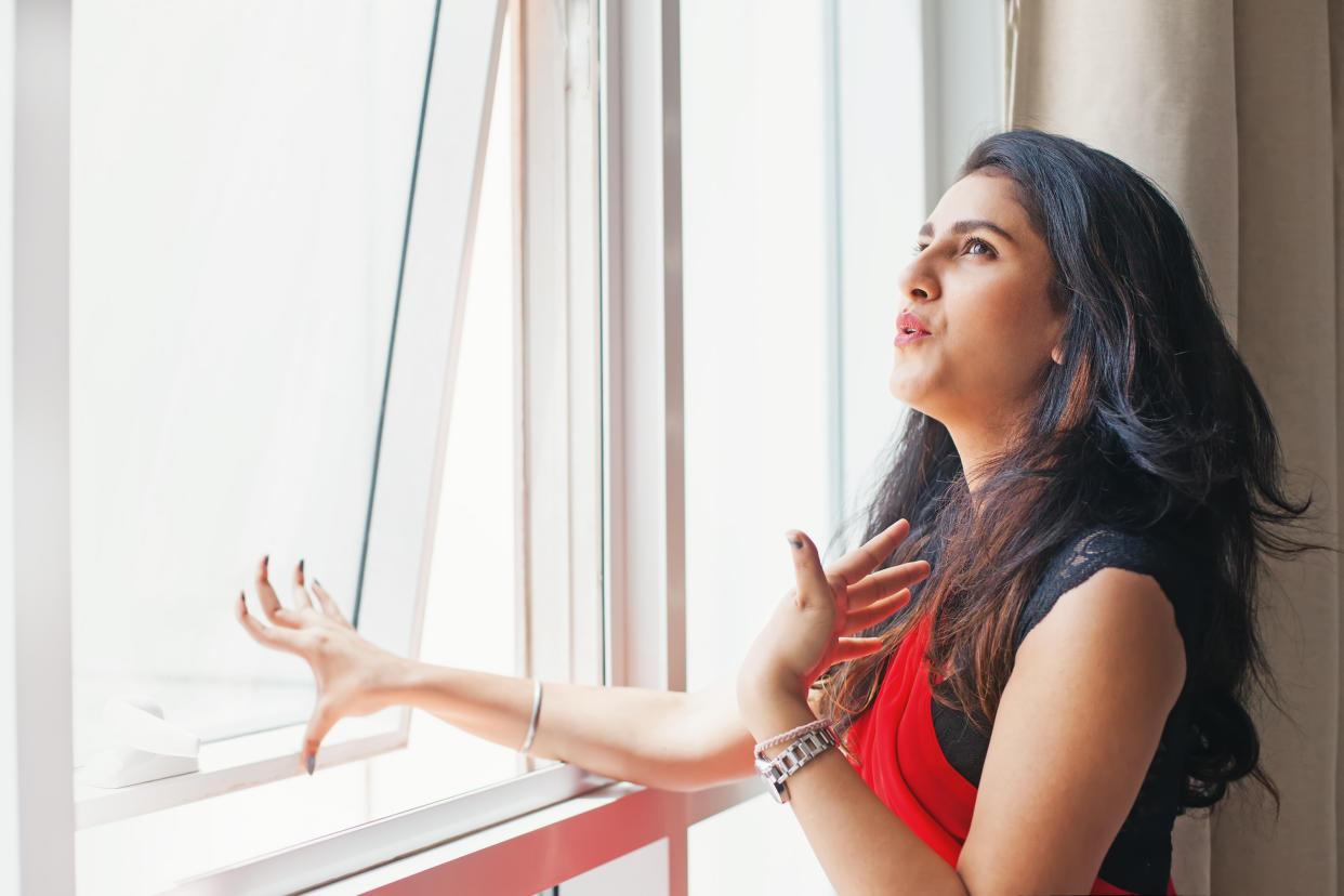 Woman opening window due to extreme heat