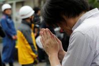 A man prays for the victims of the arson attack near the torched Kyoto Animation building n Kyoto