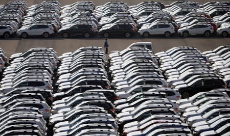 FILE PHOTO: A worker is seen among newly manufactured cars awaiting export at port in Yokohama