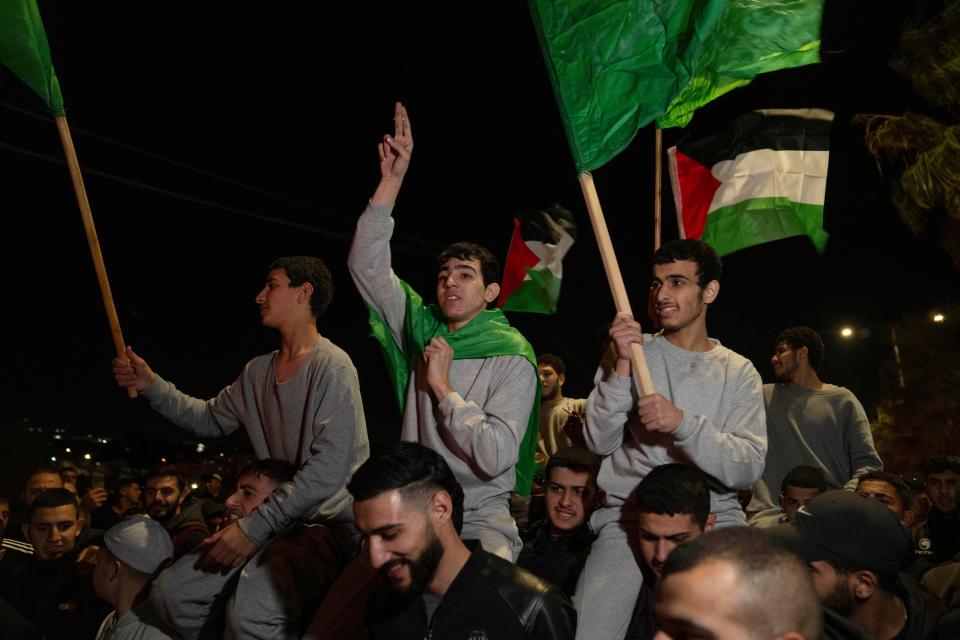 Former Palestinian prisoners who were released by the Israeli authorities, fly Palestinian and Hamas flags while they are carried on the shoulders upon their arrival in the West Bank town of Beitunia, Friday (AP)