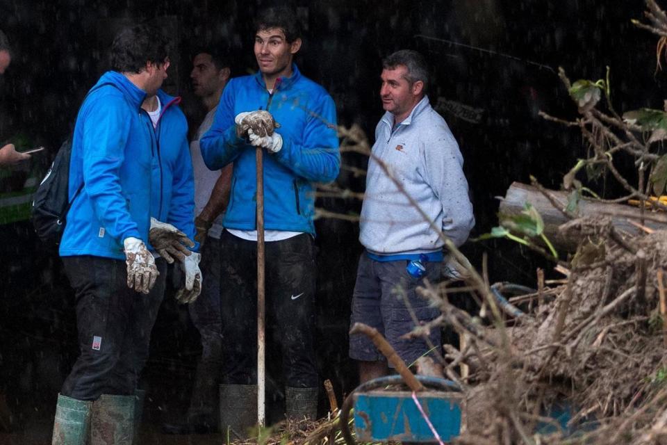 Spanish tennis player Rafael Nadal, centre, worked with residents to clear the mud from their houses