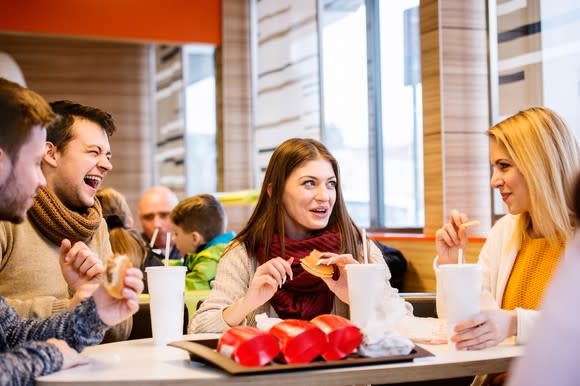 Two men and two women eating at a table in a fast-food restaurant