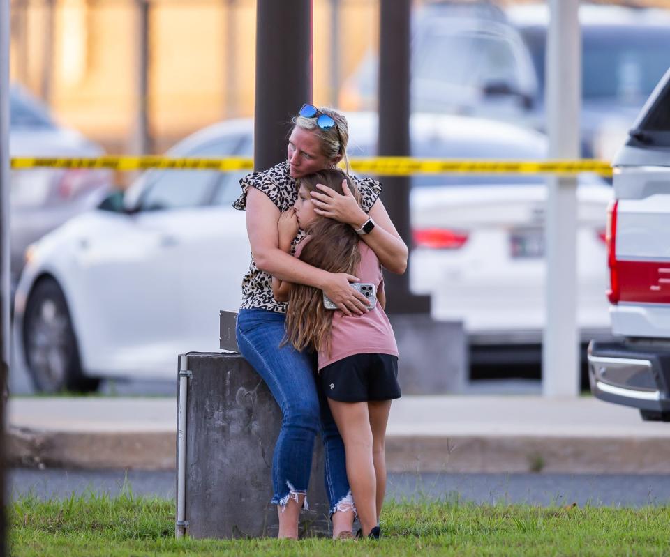 A woman comforts a child outside North Marion Middle School following a fatal shooting Wednesday night in the school’s parking lot.