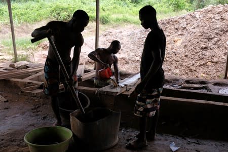 Informal gold miners process gold at a site in Bawdie