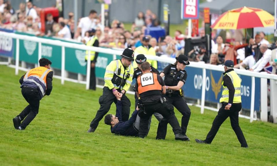 A protester is tackled by police and stewards prior to the start of the Derby.