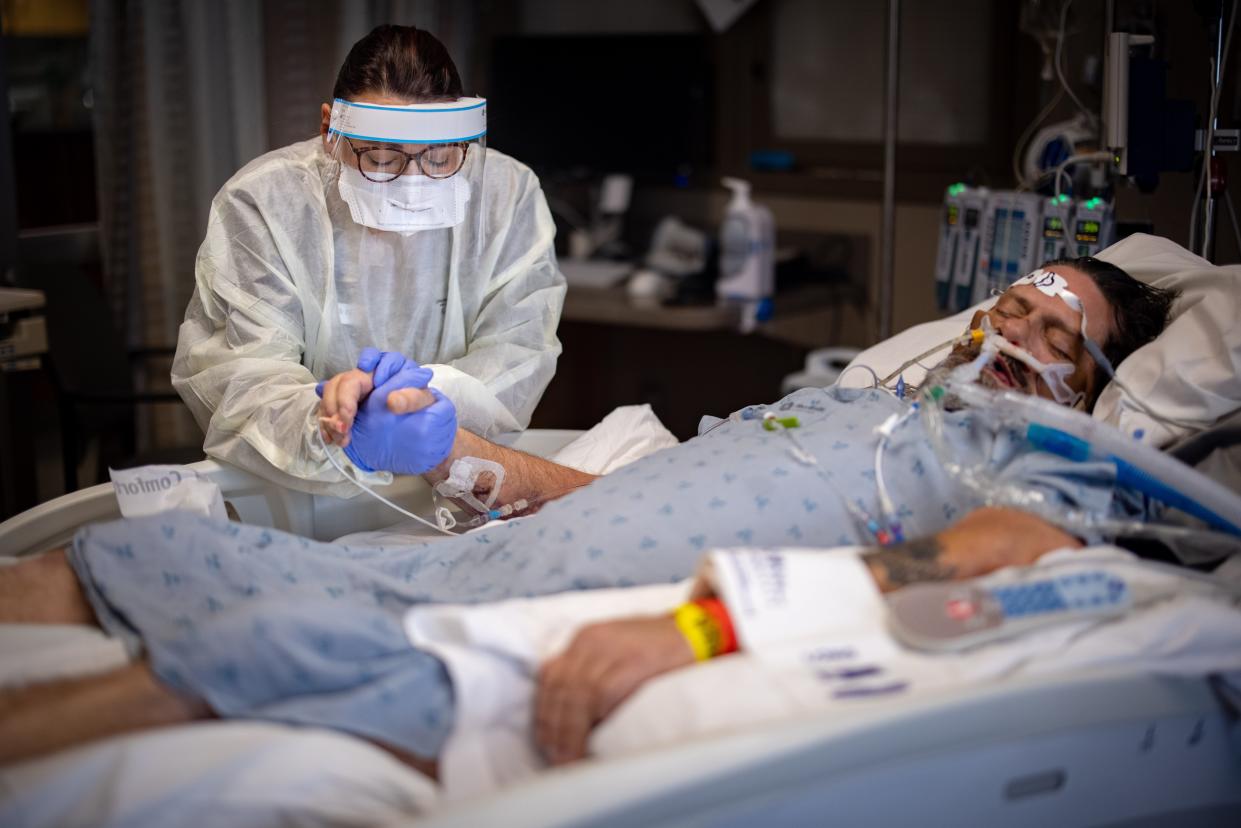 Jennifer Harrison prays as she holds the hand of her father, Rodney Eurom, while visiting him in the ICU at Mary Greeley Medical Center.