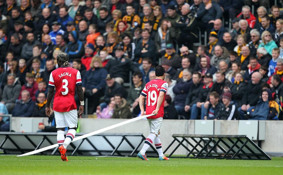 Arsenal's Santi Cazorla helps replace the advertising boards after they blew onto the pitch during their English Premier League match against Hull City at The KC Stadium, Hull, Sunday April 20, 2014. (AP Photo/PA, Lynne Cameron) UNITED KINGDOM OUT NO SALES NO ARCHIVE