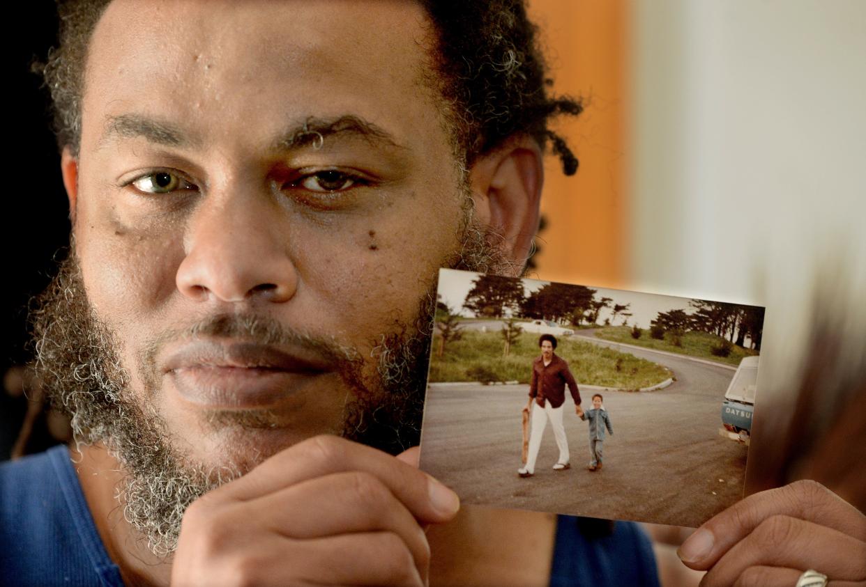 Jayson Washington of Springfield holds a photo of himself as a child walking with his father, Kevin Washington. Friends, former teammates and other supporters are looking to fully endow a scholarship in Kevin Washington's name so it is sustainable for the long term. He drowned while trying to rescue a six-year-old boy who fell in the Sangamon River in 1983.