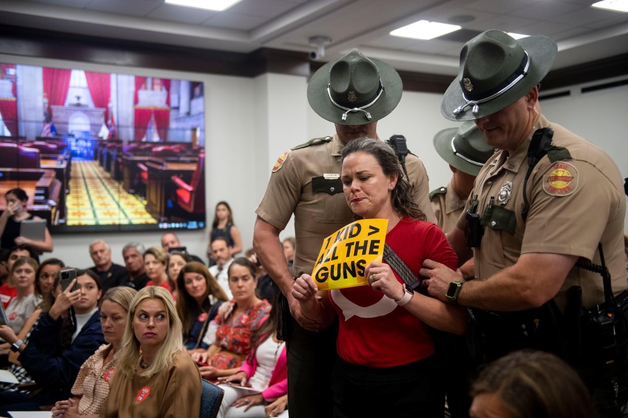 Allison Polidor is escorted out by State Troopers during a House Subcommittee meeting for holding a sign during the meeting at Cordell Hull State Office Building in Nashville , Tenn., Tuesday, Aug. 22, 2023.