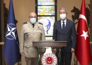 Turkey's Defense Minister Hulusi Akar, right, and Gen. Stuart Peach, the chairman of the NATO Military Committee, pose for photos before talks in Ankara, Turkey, Monday, Sept. 7, 2020. On Monday, a senior NATO official discussed the standoff as well as a NATO initiative to aimed at avoiding the risk of accidents and conflict between the two allies, Turkey and Greece, with Akar and senior military officials in Ankara. (Turkish Defense Ministry via AP, Pool)