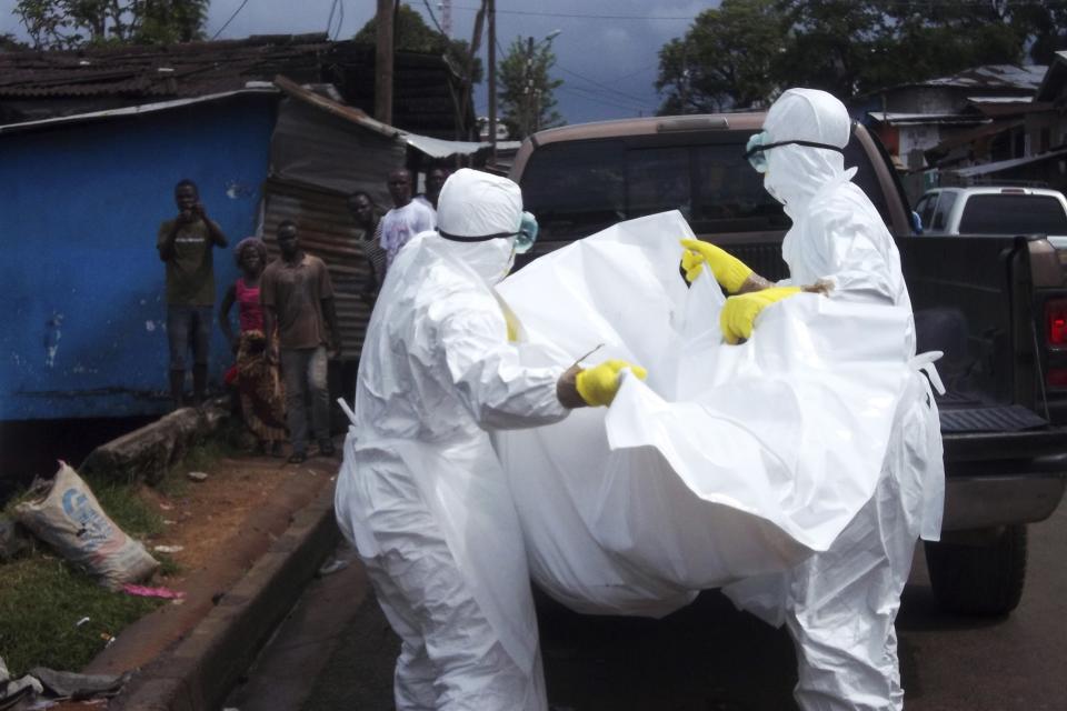 Health workers remove the body of a man believed to have died from the Ebola virus at a street in Monrovia, Liberia, October 27, 2014. REUTERS/James Giahyue (LIBERIA - Tags: HEALTH DISASTER)